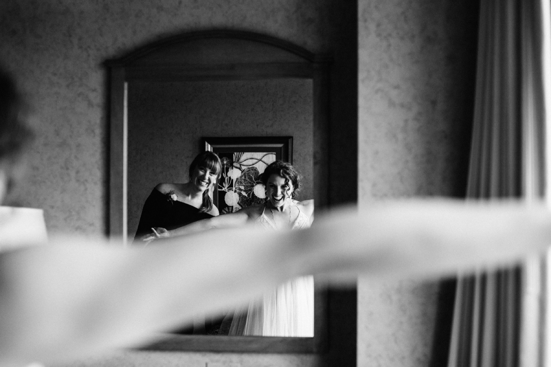 bride and maid of honor pose in mirror at hotel captain cook