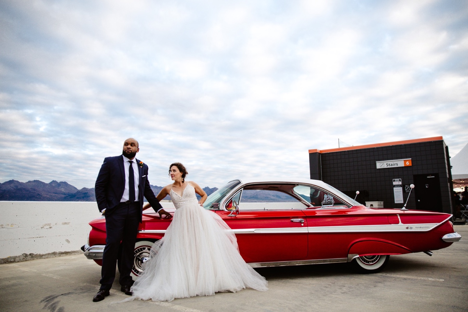 bride and groom with vintage red car on rooftop of easy park garage in downtown anchorage