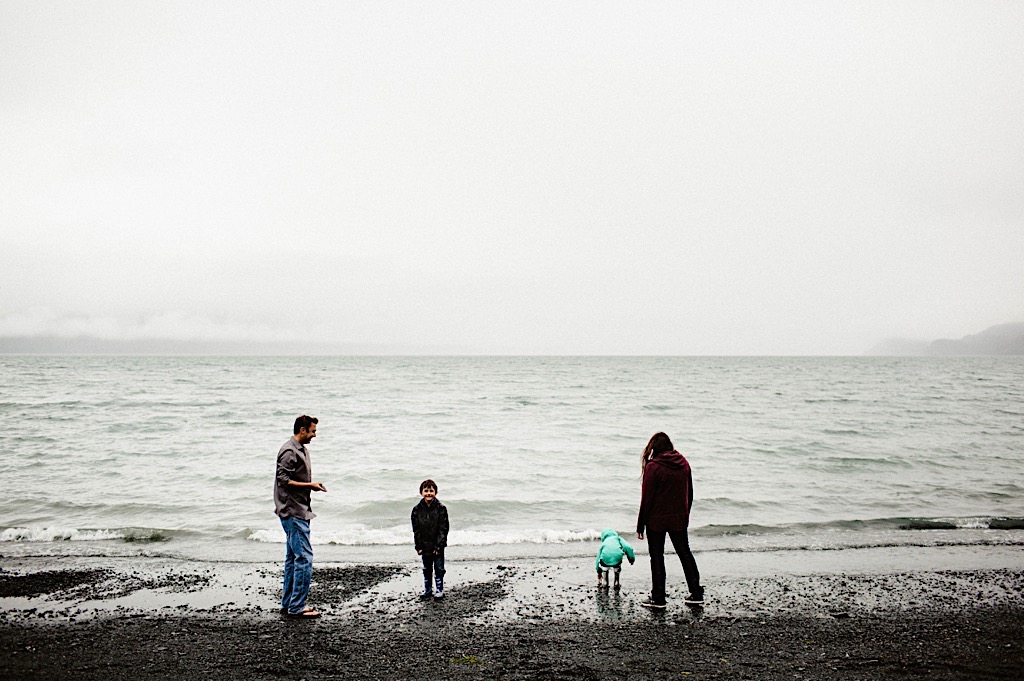 family of four skipping rocks at the beach 