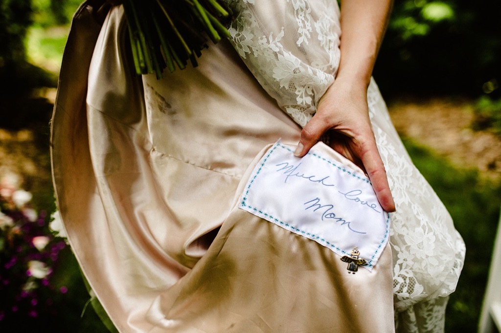bride shows embroidery from her mom on her wedding dress