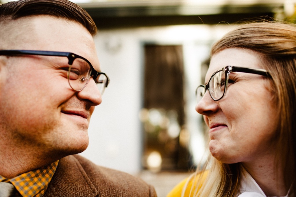 couple wearing retro glasses look lovingly at each other 