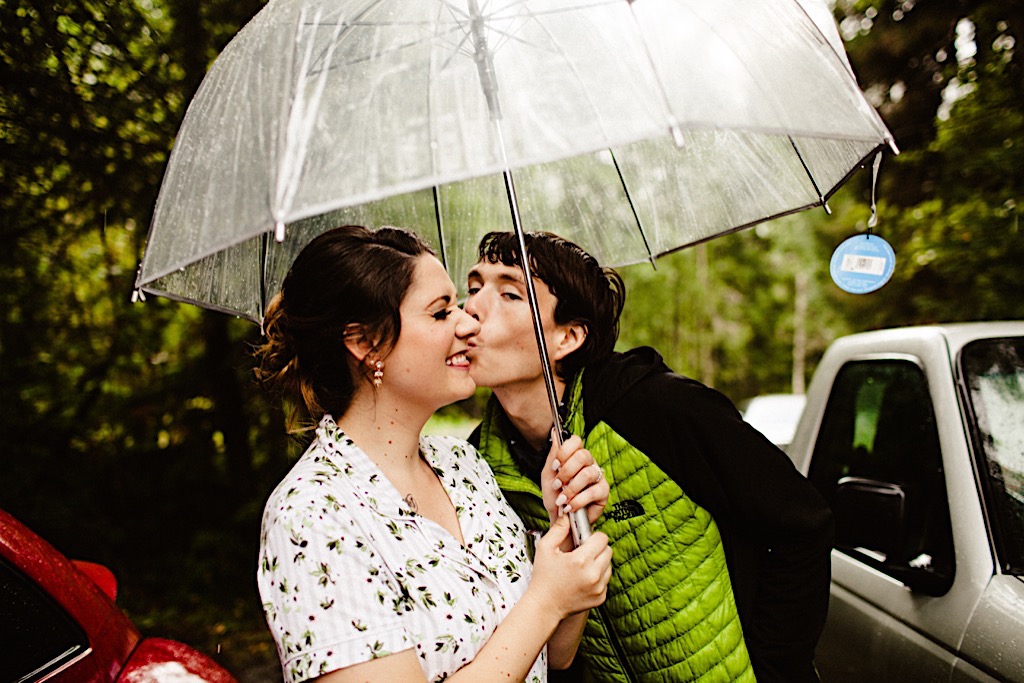 brother of bride steals a kiss under umbrella