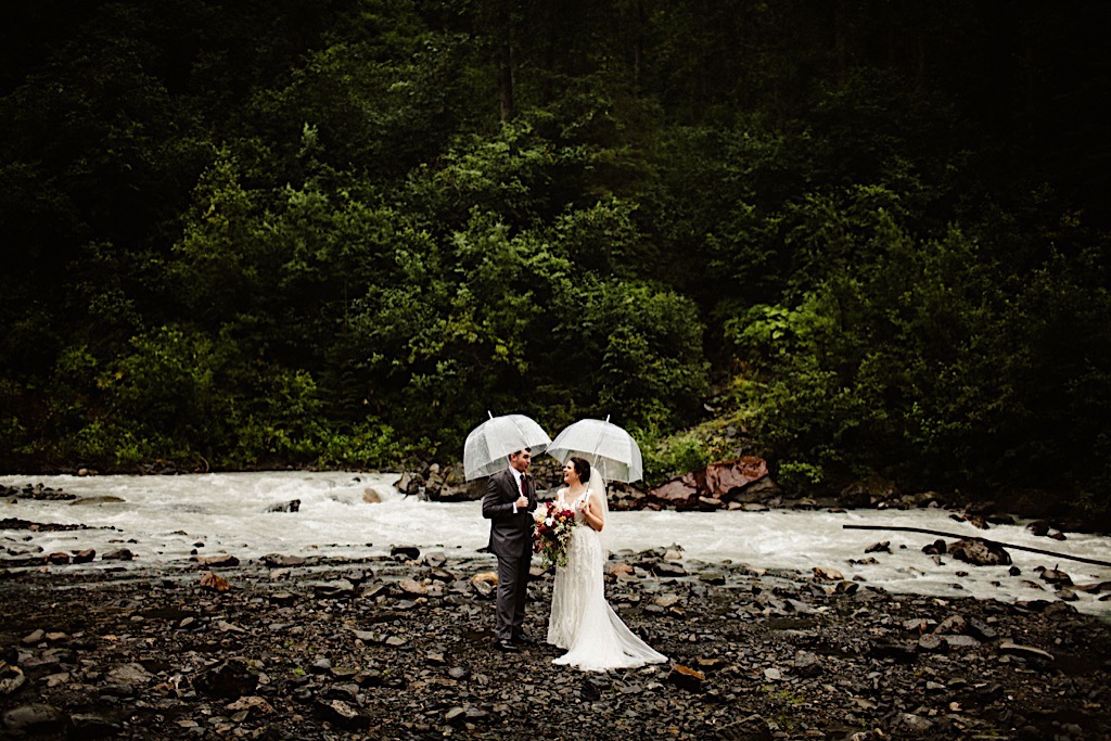 bride and groom with umbrellas at crow creek 