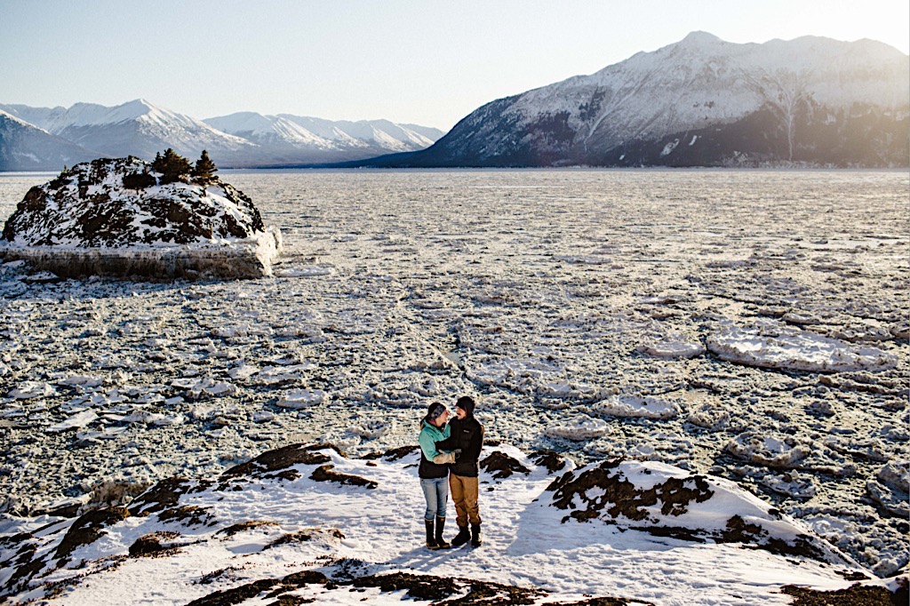 couple in the snow surrounded by mountains and ice at beluga point
