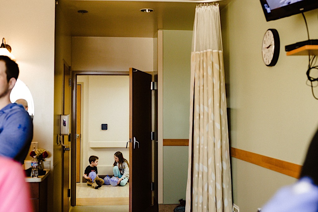 little boy and girl in hospital hallway with glove balloons