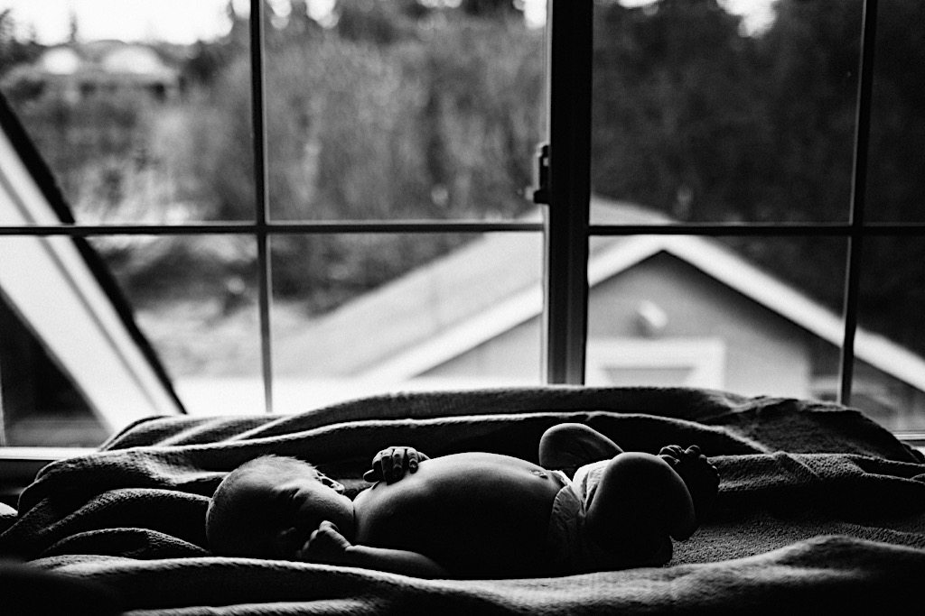 newborn baby laying by window