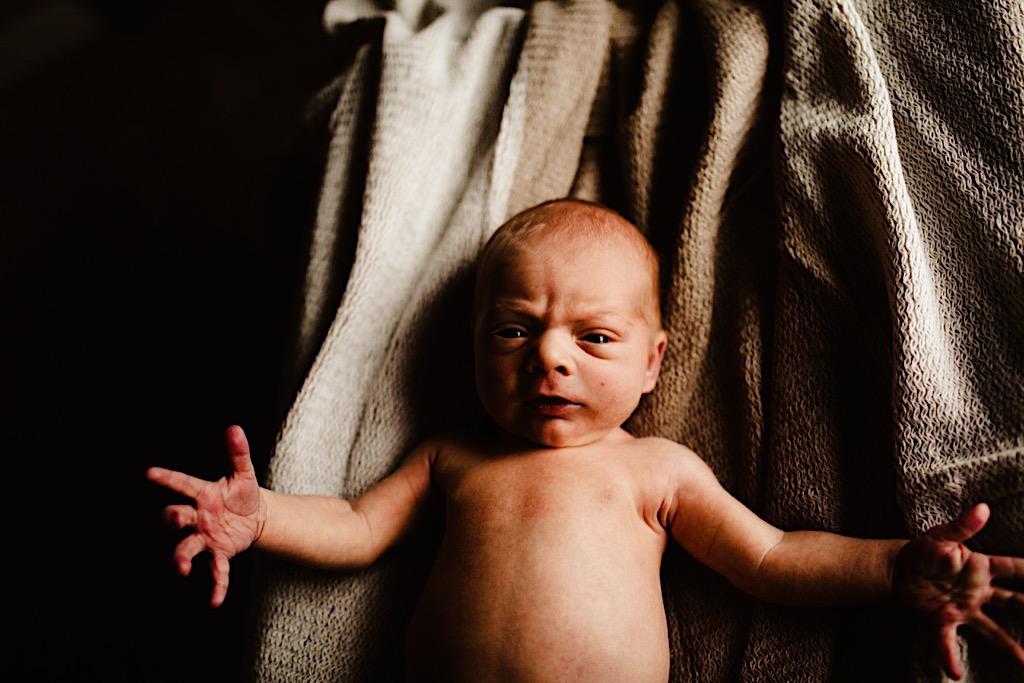 newborn baby grimacing with extended arms 