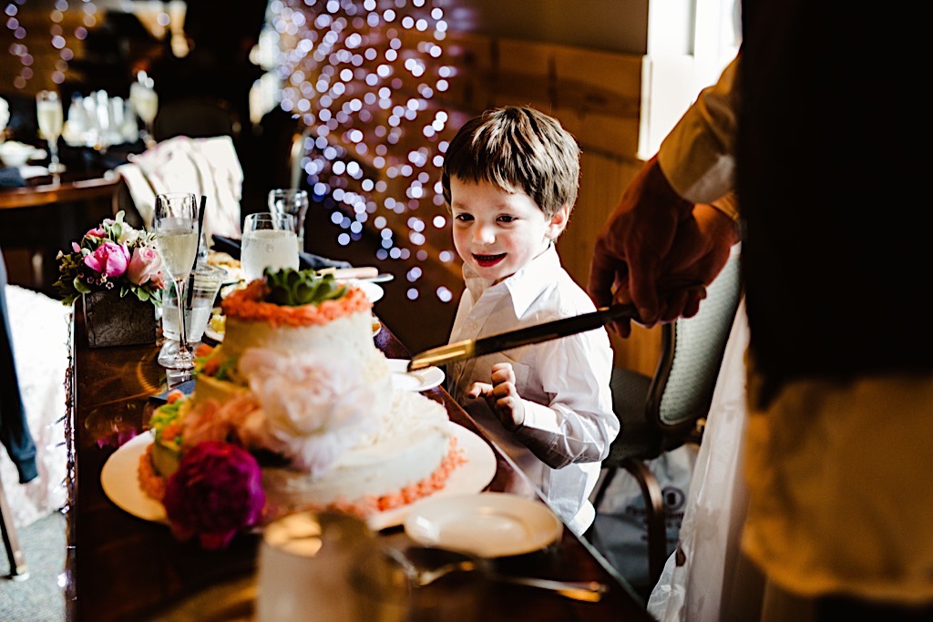 little boy looks longingly at wedding cake 