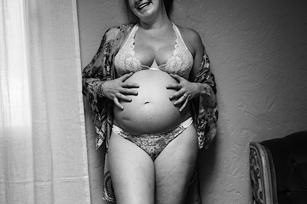 woman laughing holding her pregnant b