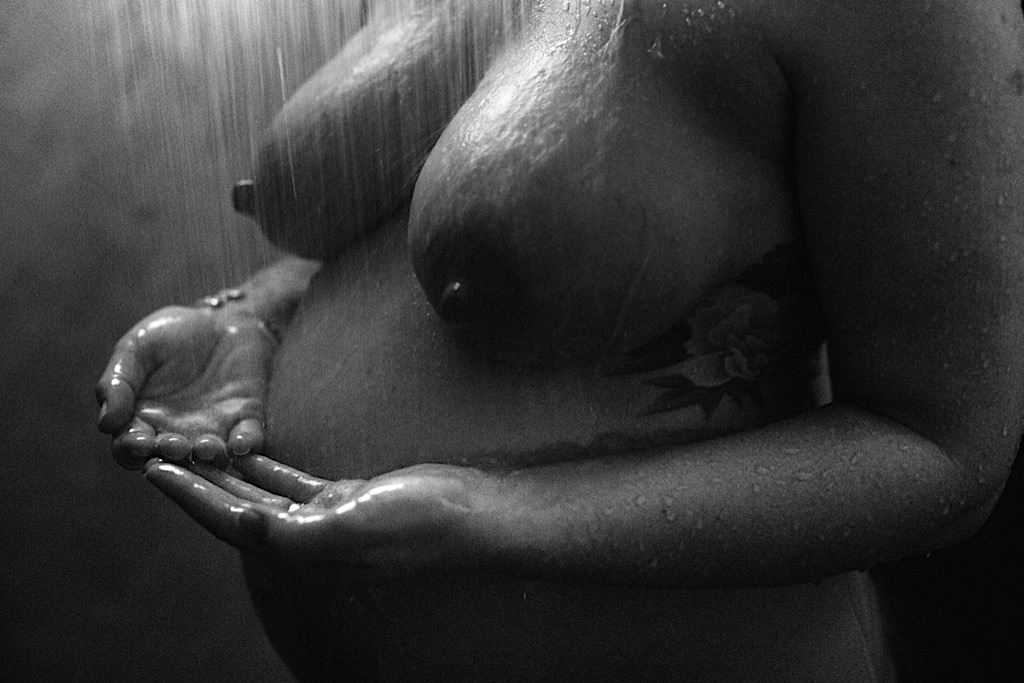 nude woman catches water in her hands in the shower
