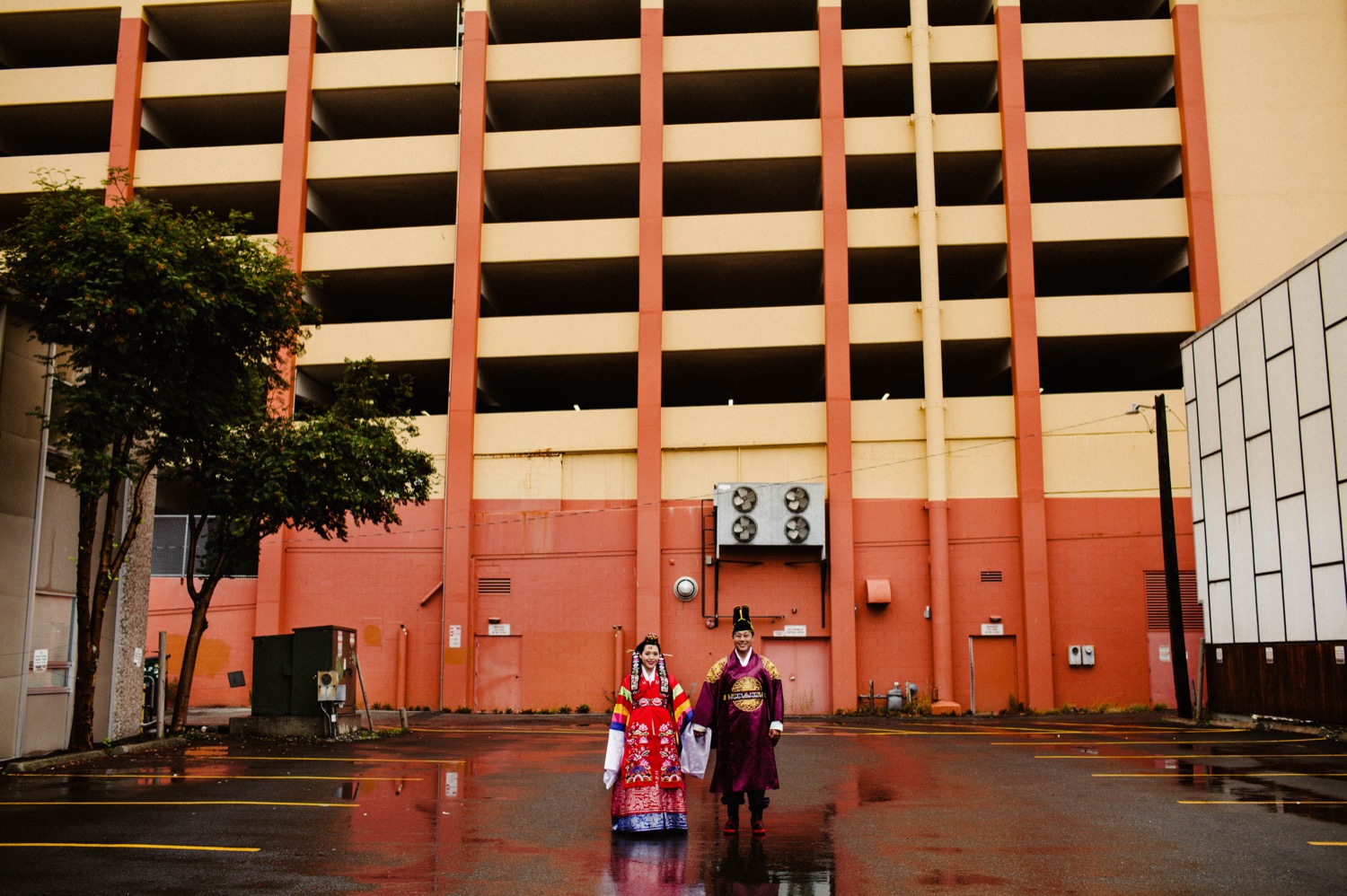 bride and groom in traditional korean clothing in front of parking garage