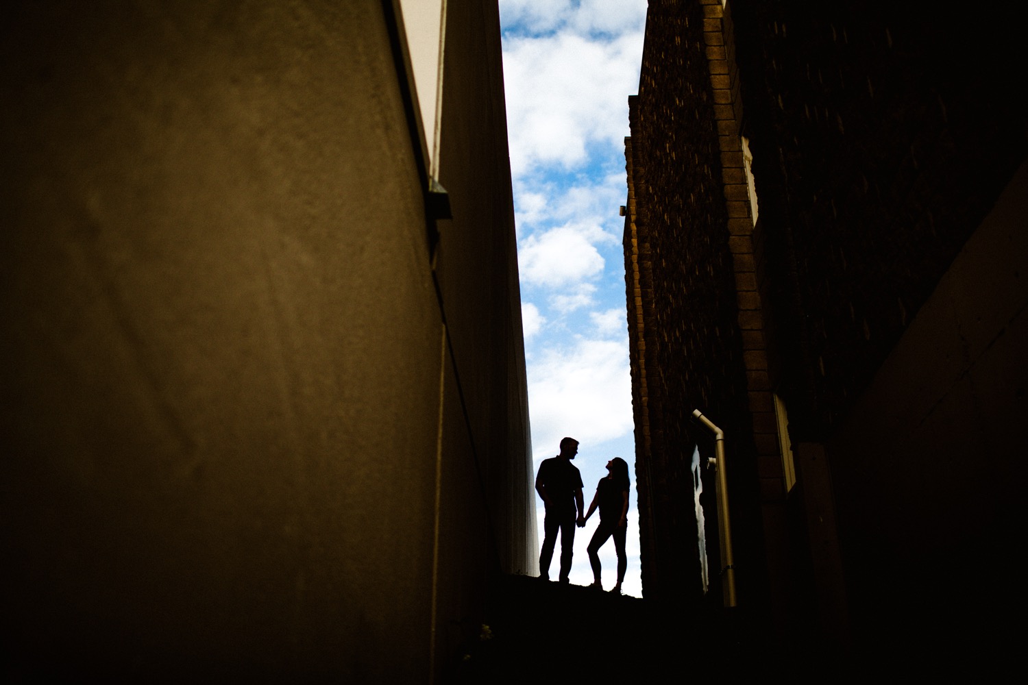 silhouetted couple stands in alley