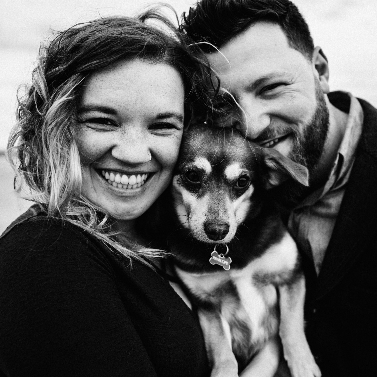 couple smiling with dog between their faces