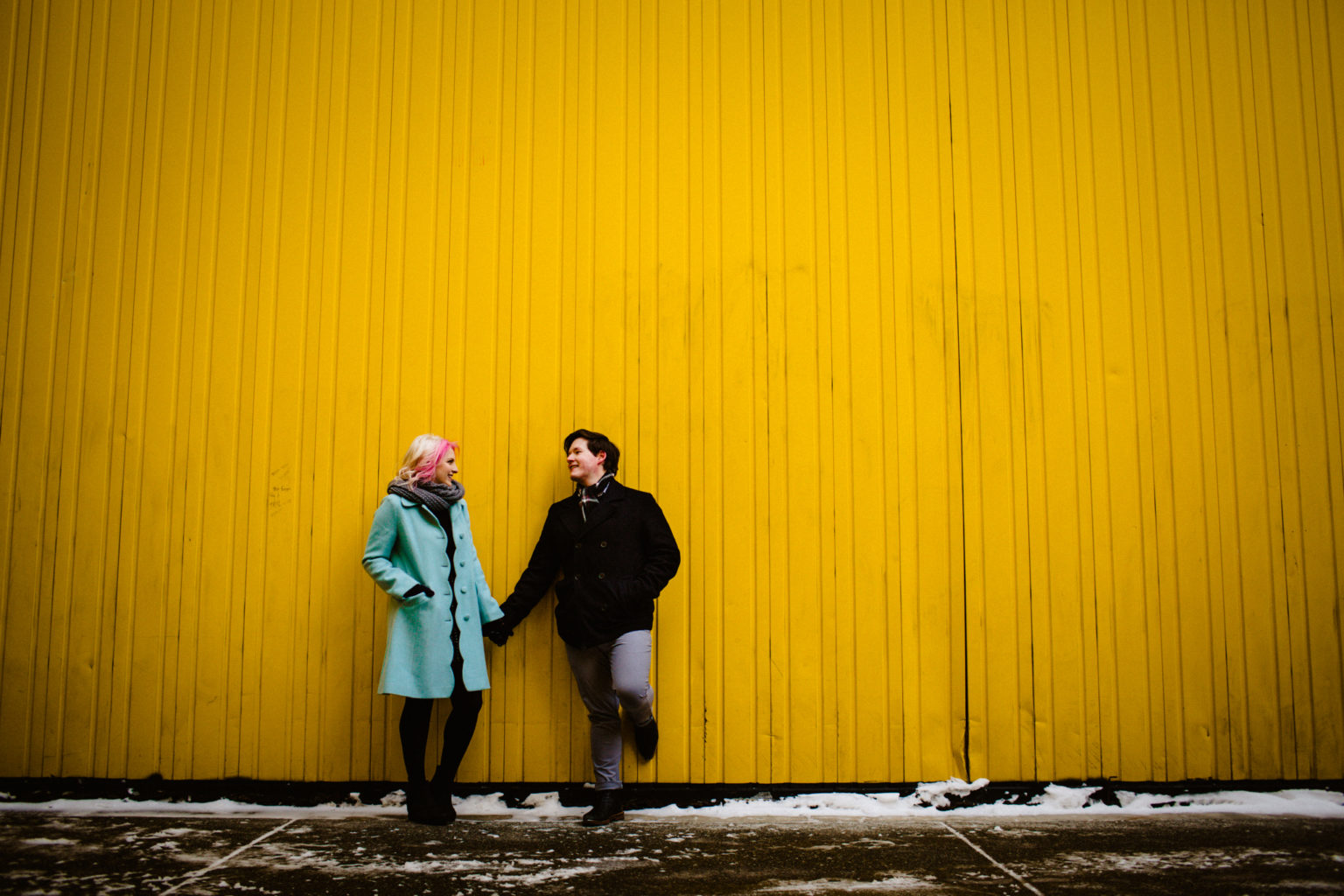 couple standing against yellow wall at sunshine plaza