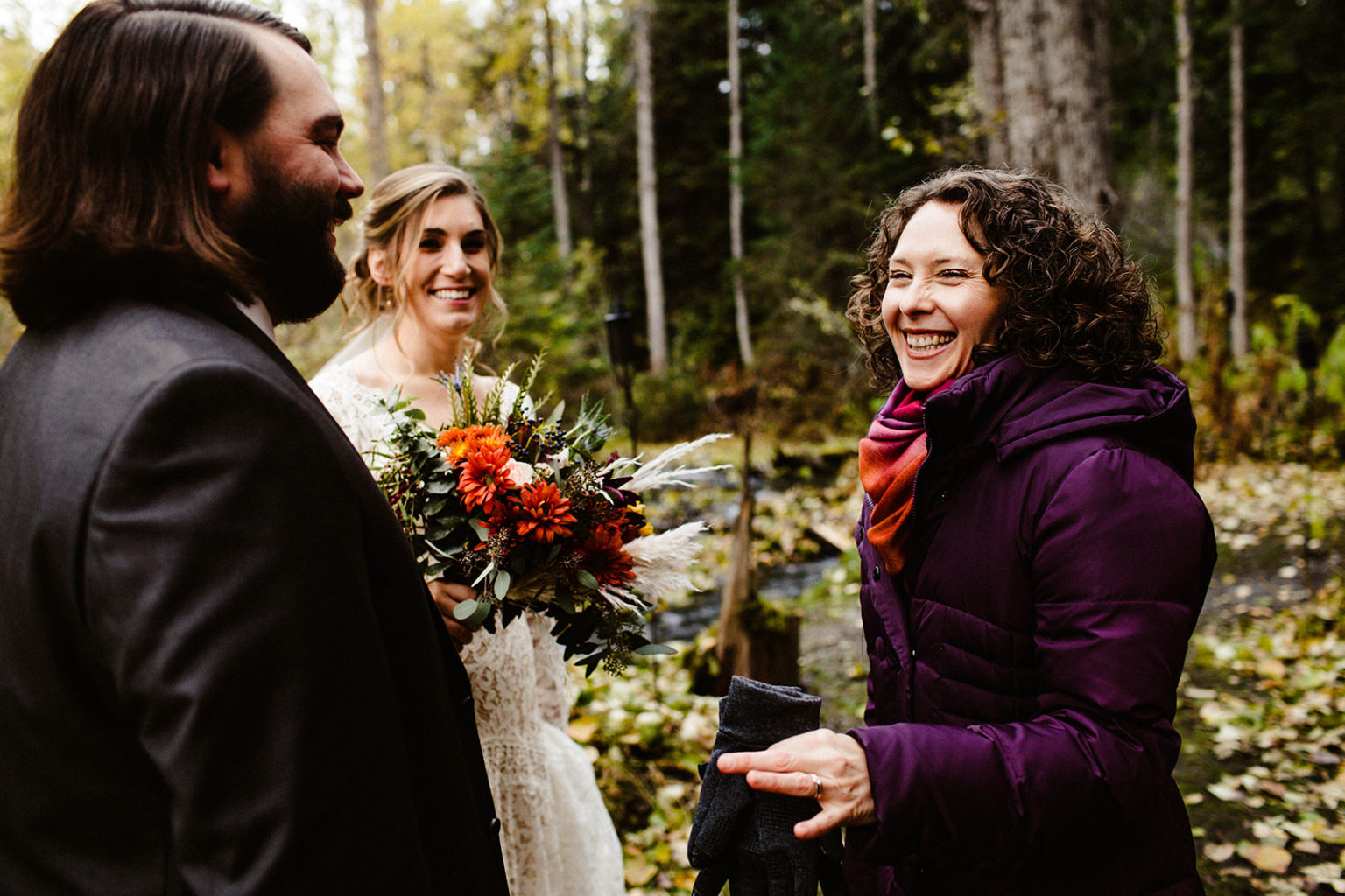 officiant smiles talking to bride and groom at raven glacier lodge wedding