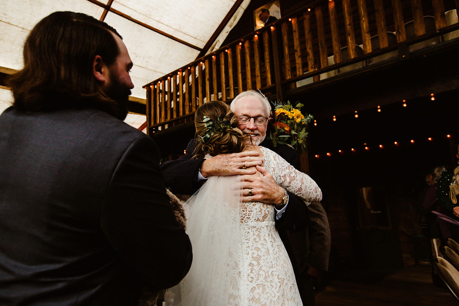 father of groom gives bride a hug