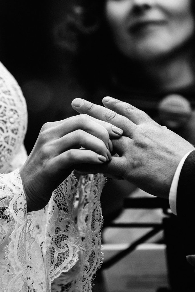 close up of bride and groom's hands exchanging wedding rings
