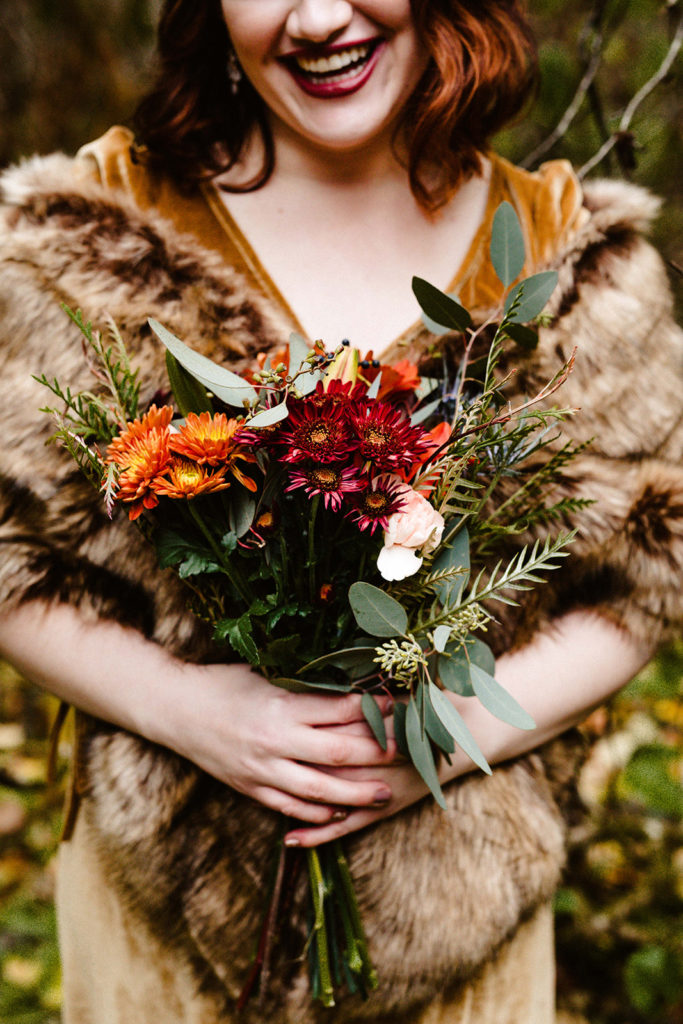 bridesmaid in fur holding fall floral bouquet